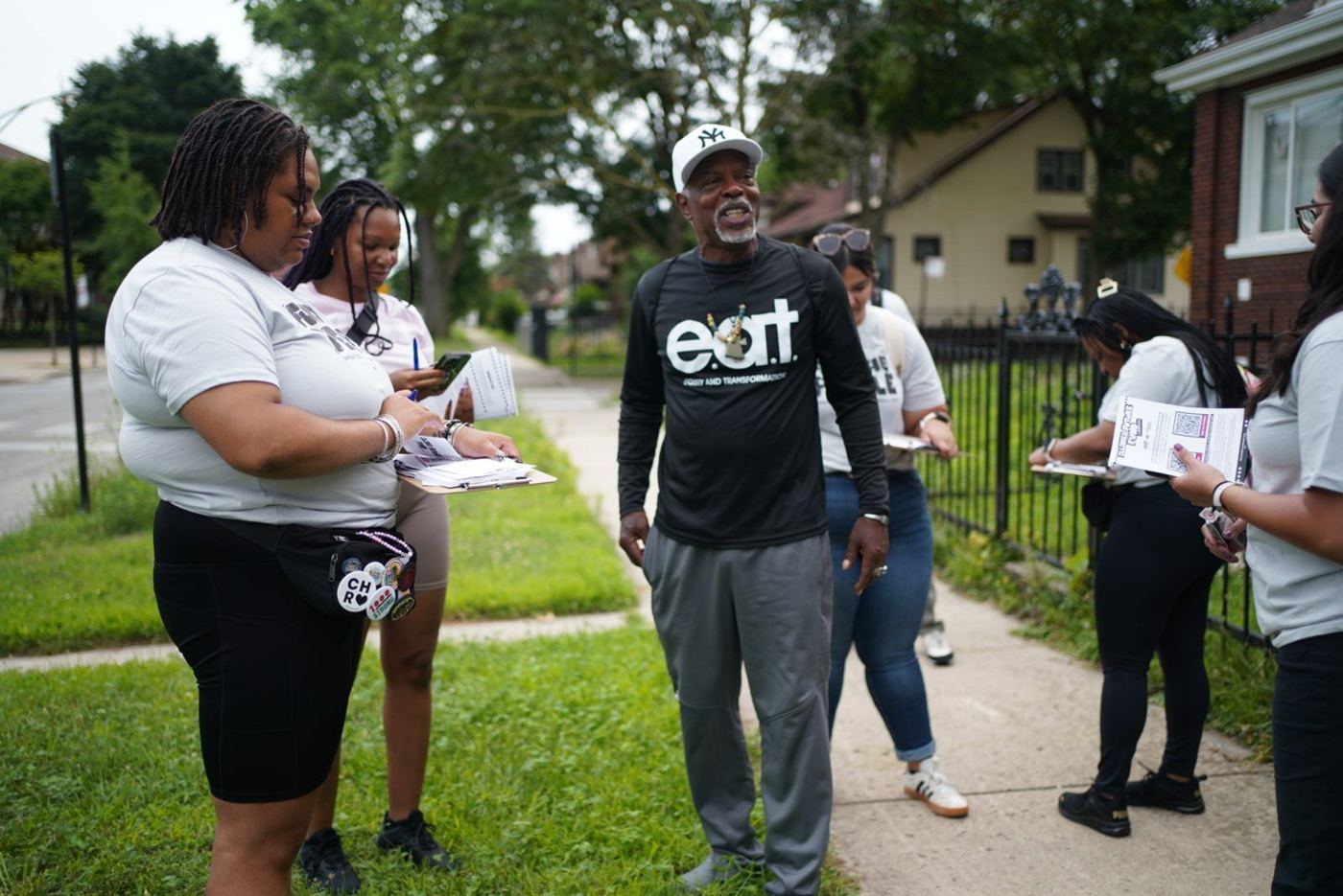 Canvassers talk with a neighbor on the sidewalk
